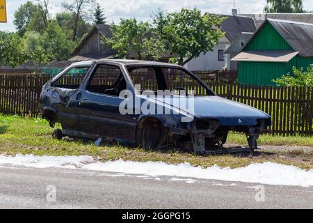 Une voiture de tourisme brûlée sur le côté de la route. Il y a des restes de mousse autour de la voiture, que les pompiers ont utilisé pour éteindre l'incendie. Banque D'Images