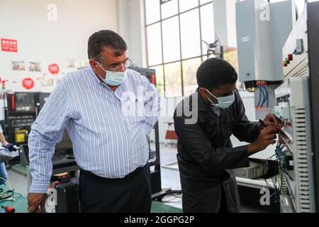 Le Caire, Égypte. 16 août 2021. Mohamed Ahmed Awad, directeur exécutif de l'atelier Luban à l'université d'Ain Shams en Égypte, vérifie le fonctionnement de la connexion de circuit par le stagiaire Ibrahim Abdel Ghaffar à l'installation et à la mise en service de la zone de formation de Luban à l'université du Caire, en Égypte, le 16 août 2021. POUR ALLER AVEC "Feature: L'atelier professionnel chinois en Egypte prépare les diplômés pour le marché du travail" crédit: Sui Xiankai/Xinhua/Alamy Live News Banque D'Images