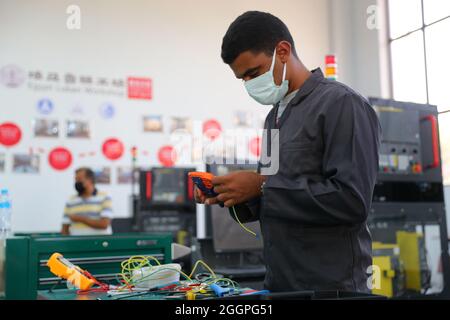 Le Caire, Égypte. 16 août 2021. Le stagiaire Ibrahim Abdel Ghaffar apprend la connexion de circuit à la zone de formation à l'installation et à la mise en service de la commande numérique par ordinateur (CNC) de l'atelier Luban à l'Université Ain Shams au Caire, en Égypte, le 16 août 2021. POUR ALLER AVEC "Feature: L'atelier professionnel chinois en Egypte prépare les diplômés pour le marché du travail" crédit: Sui Xiankai/Xinhua/Alamy Live News Banque D'Images