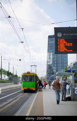 POZNAN, POLOGNE - 28 juillet 2017 : un cliché vertical des personnes qui attendent à un arrêt de transport en commun avec un tramway vert dans le centre-ville Banque D'Images