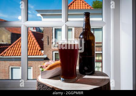 Boire de la bière foncée avec sandwich au poisson fumé à l'anguille avec vue sur la rue dans la vieille ville de Zierikzee, Zeeland, pays-Bas, gros plan Banque D'Images