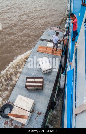 AMAZONE, BRÉSIL - 30 JUIN 2015 : l'équipage charge la cargaison entre le bateau passager et un petit bateau sur l'Amazone. Banque D'Images