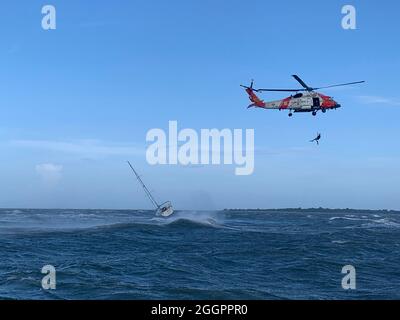 Chincoteague, États-Unis d'Amérique. 1er septembre 2021. Chincoteague, États-Unis d'Amérique. 01 septembre 2021. Un nageur de secours de la Garde côtière américaine fait une descente en rappel pour secourir trois marins bloqués dans le port de Chincoteague par temps violent alors que les restes de l'ouragan Ida sont passés par le 1er septembre 2021 à Chincoteague, en Virginie. Crédit : OPC Ross Comstock/Garde côtière/Alamy Live News Banque D'Images