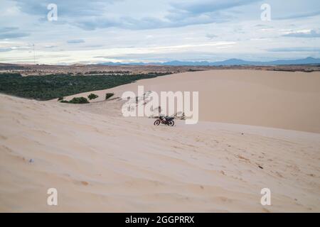 Vue imprenable sur la moto garée sur les dunes de sable dans le désert. Journée ensoleillée pendant les vacances d'été. Dunes de sable. Moto dans le désert. Banque D'Images