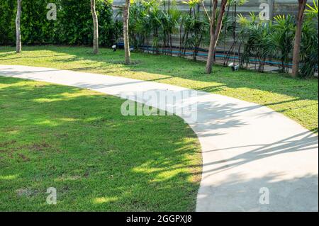 Chemin incurvé à travers la pelouse verte dans le jardin sous le soleil Banque D'Images