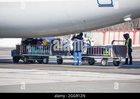 chargement des bagages à l'aéroport en hiver. Bagages dans les chariots près de l'avion en hiver. Avion passager en hiver à l'aéroport a chargé des bagages avant le départ Banque D'Images