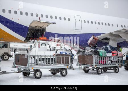 chargement des bagages à l'aéroport en hiver. Bagages dans les chariots près de l'avion en hiver. Avion passager en hiver à l'aéroport a chargé des bagages avant le départ Banque D'Images