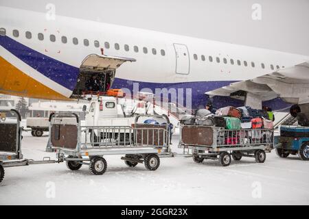 chargement des bagages à l'aéroport en hiver. Bagages dans les chariots près de l'avion en hiver. Avion passager en hiver à l'aéroport a chargé des bagages avant le départ Banque D'Images