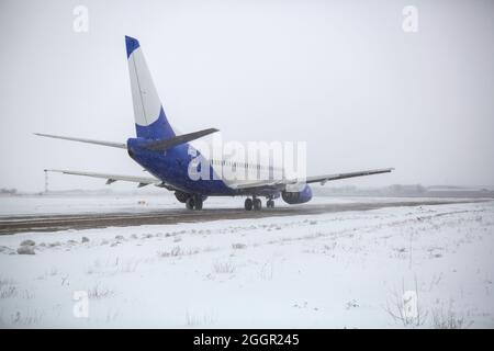 Avion de ligne sur piste en blizzard. Avion en train de rouler sur la piste d'atterrissage pendant une forte neige. Avion passager dans la neige à l'aéroport. Banque D'Images