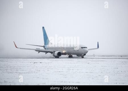 Avion de ligne sur piste en blizzard. Avion en train de rouler sur la piste d'atterrissage pendant une forte neige. Avion passager dans la neige à l'aéroport. Banque D'Images