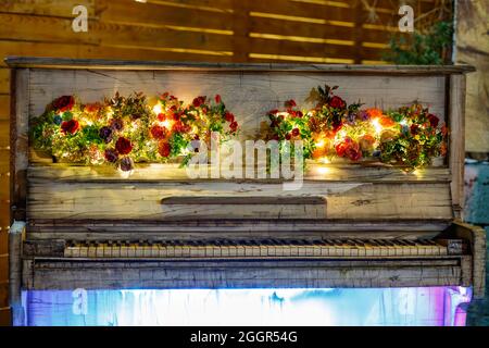 NightShot de piano blanc rétro décoratif avec lumières LED multicolores décorées de décorations florales et cascade d'eau Banque D'Images