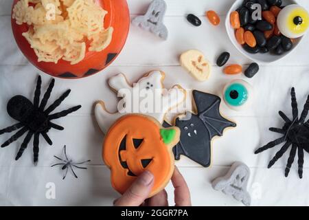 Femme tenant main le cookie d'halloween de table de fête avec d'autres bonbons et collations Banque D'Images