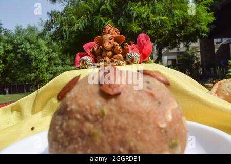 Attention sélective du beau seigneur Ganesha idol sur fond adoré pendant le festival de Ganesh chaturthi avec laddu en premier plan. Assis Ganpati dur Banque D'Images