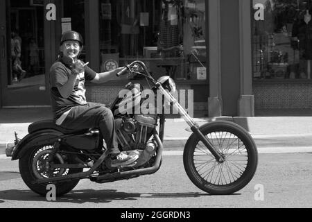 Un jeune homme fait le tour de sa moto Harley Davidson le long d'une rue du centre-ville de Santa Fe, Nouveau-Mexique. Banque D'Images