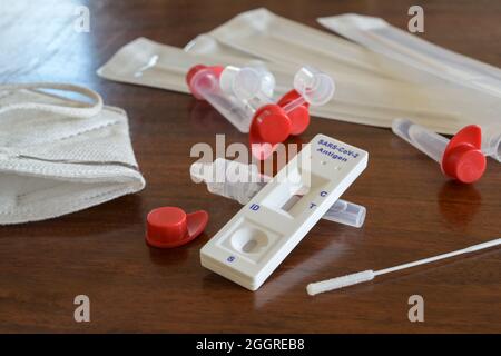 Test automatique d'antigène Covid-19 rapide avec résultat négatif, écouvillons nasaux, tubes et dispositif de détection sur une table en bois, utilisé pour le diagnostic de masse à la maison, à Banque D'Images