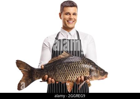 Youn homme portant un tablier et tenant un gros poisson de carpe isolé sur fond blanc Banque D'Images