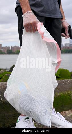 Un sac poubelle dans la main d'un homme Banque D'Images