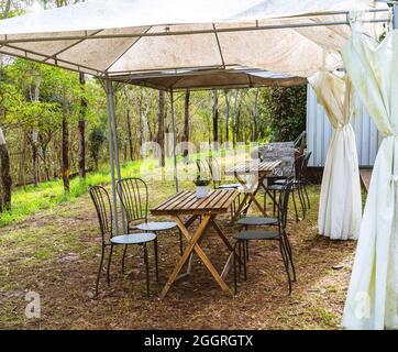 Café en plein air avec table et chaises rustiques et maigres à flanc de colline sous une tente à mâcher Banque D'Images