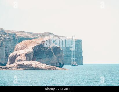 GOZO, MALTE - 09 août 2021 : un coup de feu d'un yacht d'ancre célèbre au loin de la roche de champignon de Gozo et du flanc de falaise. Banque D'Images