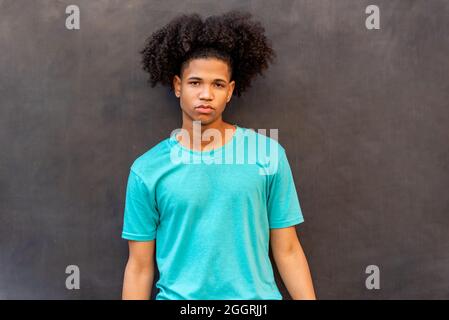 Portrait du jeune afro latin contre un mur noir Banque D'Images