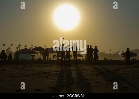 Silhouettes de personnes jouant avec une balle à Sunrise sur Huntington Beach California USA Banque D'Images