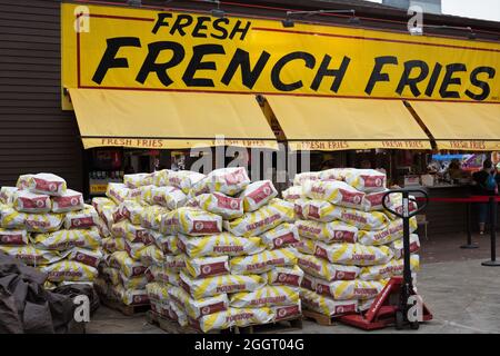 Grandes piles de sacs de pommes de terre à côté d'un stand de frites à la foire de l'État du Minnesota. Banque D'Images