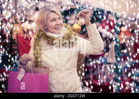 Bonne femme mûre en guirlande avec des jouets de Noël à la foire Banque D'Images