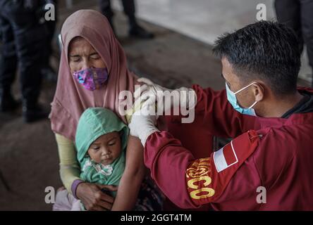 Makassar, Sulawesi du Sud, Indonésie. 3 septembre 2021. Un mendiant féminin qui tient son enfant est injecté avec le vaccin Covid-19 par des agents de santé de la brigade mobile de police de Sulawesi du Sud. Cette activité de vaccination gratuite a été effectuée au quartier général de la brigade mobile de la police de Sulawesi du Sud pour atteindre l'objectif de vaccination des Sulawesi du Sud, jusqu'à 80 pour cent. (Credit image: © Herwin Bahar/ZUMA Press Wire) Credit: ZUMA Press, Inc./Alamy Live News Banque D'Images