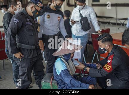 Makassar, Sulawesi du Sud, Indonésie. 3 septembre 2021. Un mendiant est soumis à un examen par un agent de santé de la brigade mobile de police de Sulawesi du Sud avant son tour pour se faire vacciner. Cette activité de vaccination gratuite a été effectuée au quartier général de la brigade mobile de la police de Sulawesi du Sud pour atteindre l'objectif de vaccination des Sulawesi du Sud, jusqu'à 80 pour cent. (Credit image: © Herwin Bahar/ZUMA Press Wire) Credit: ZUMA Press, Inc./Alamy Live News Banque D'Images