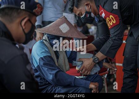 Makassar, Sulawesi du Sud, Indonésie. 3 septembre 2021. Un mendiant est soumis à un examen par un agent de santé de la brigade mobile de police de Sulawesi du Sud avant son tour pour se faire vacciner. Cette activité de vaccination gratuite a été effectuée au quartier général de la brigade mobile de la police de Sulawesi du Sud pour atteindre l'objectif de vaccination des Sulawesi du Sud, jusqu'à 80 pour cent. (Credit image: © Herwin Bahar/ZUMA Press Wire) Credit: ZUMA Press, Inc./Alamy Live News Banque D'Images