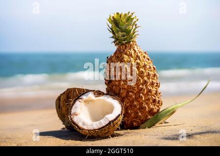 ananas frais et noix de coco dans un paysage tropical. La noix de coco est décomposée en 2 moitié sur le sable sur le fond de la mer Banque D'Images