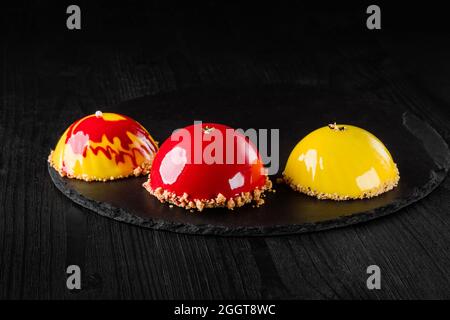 Beaux gâteaux couverts de glaçage jaune et rouge brillant. Concept design desserts pâtisserie Banque D'Images