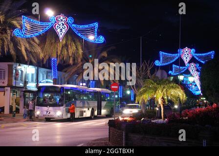 Centre ville rue commerçante à Noël la nuit avec des bus en premier plan, la Cala de Mijas, Costa del, Espagne. Banque D'Images