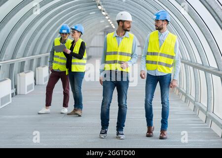 les travailleurs qui se trouvent dans des gilets à haute visibilité traversent le tunnel Banque D'Images