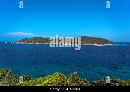 Une petite île à la distance sur le fond du ciel bleu et senega belle mer transparente. Arbres verts au premier plan. Banque D'Images