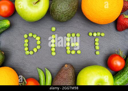 Régime mot fait de pois verts encadrés avec des fruits et des légumes assortis sur un fond noir texturé. Concept de régime alimentaire biologique équilibré. Banque D'Images