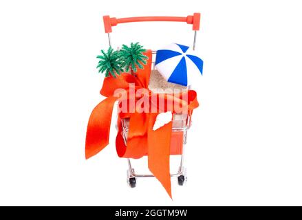 Plage tropicale aménagée dans une petite voiturette avec un gros noeud rouge isolé sur du blanc. Offrez des vacances à la plage. Banque D'Images