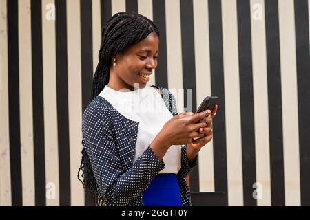 jeune femme africaine se sentant excitée en utilisant son téléphone portable Banque D'Images