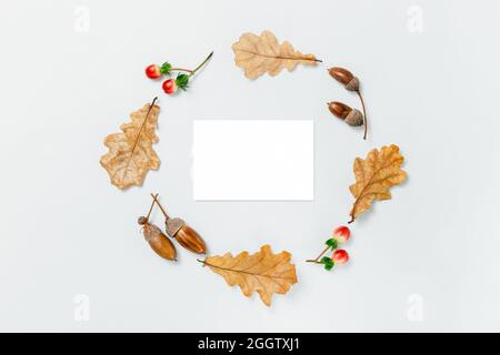 Composition minimale d'automne. Couronne d'acornes, feuilles d'aok dorées et baies rouges sur fond blanc. Maquette d'automne pour le texte. Élément design d'automne, FL Banque D'Images