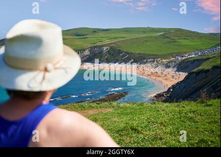 Flou de femme d'âge moyen avec chapeau de paille en premier plan devant la plage de sable de Tagle, Suances, Cantabria, Espagne, Europe Banque D'Images