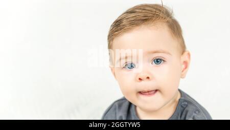 Portrait de tête de bébé adorable souriant, montre la langue. Espace de copie, arrière-plan blanc. Banque D'Images