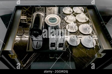 Cafetière expresso et station avec tasses et bouteilles d'eau de marque dans le minibar de l'hôtel Ritz Carlton Banque D'Images