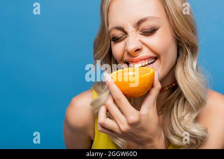 bonne jeune femme en maillot jaune orange mordant isolé sur bleu Banque D'Images