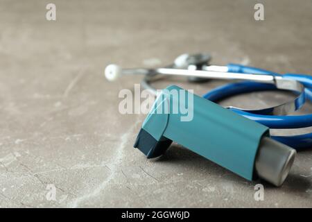 Inhalateur pour asthme et stéthoscope sur table texturée grise Banque D'Images