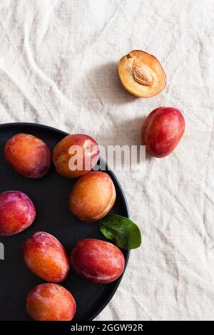 Prunes Victoria fraîches sur une assiette noire. Banque D'Images