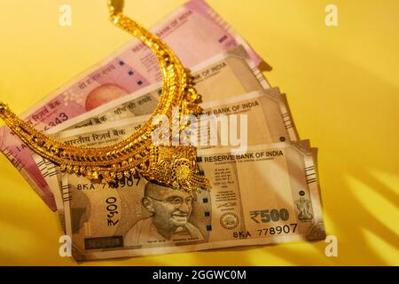 Bijoux d'or conservés sur des billets en monnaie indienne. Banque D'Images