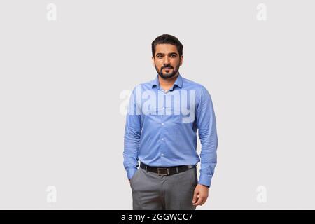 Portrait d'un homme debout dans des vêtements formels souriant sur fond blanc. Banque D'Images