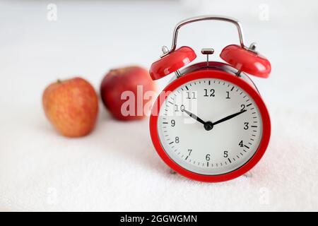 Radio-réveil rouge posé sur une serviette blanche près de la pomme Banque D'Images