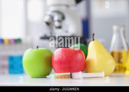 Seringue avec des médicaments à proximité des fruits sur fond de microscope de gros plan Banque D'Images