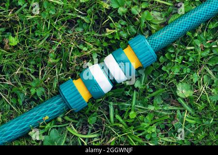 Tuyaux d'irrigation de jardin connectés à un connecteur de tuyau en plastique moderne pour une connexion rapide couchée sur l'herbe de près Banque D'Images